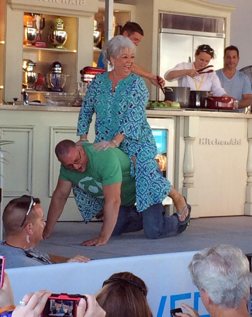 Paula Deen gets a ride across stage from Food Network star Robert Irvine during a cooking demo at the South Beach Wine and Food Festival in Miami, Fla., Sunday, Feb. 23, 2014. Deen continued maneuvering for a comeback Sunday, turning a beachside cooking demonstration into a public apology for the racist comments that decimated her career last year. (AP Photo/J.M. Hirsch)