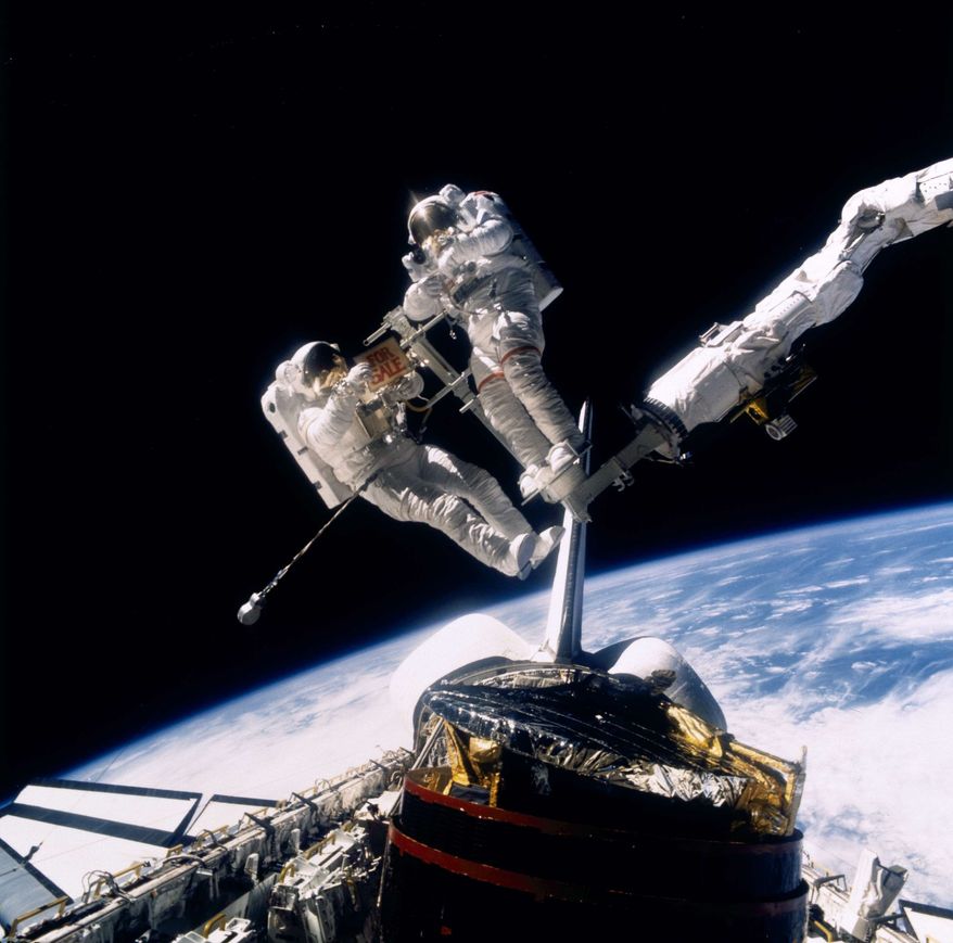 Astronaut Dale A. Gardner, left, holds a "For Sale" sign, making light of the status of the retrieved communications satellite below in the cargo bay of the space shuttle Discovery, Nov. 1984. Astronaut John Allen IV stands on the end of the arm of the Remote Manipulator System. (AP Photo/NASA)