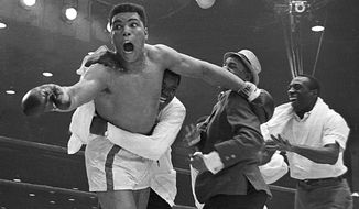 Cassius Clay&#39;s handlers hold him back as he reacts after he is announced the new heavyweight champion of the world on a seventh round technical knockout against Sonny Liston at Convention Hall in Miami Beach, Fla., on Feb. 25, 1964.  (AP Photo)