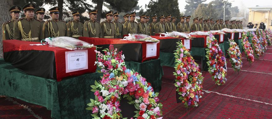 Members of the Honor Guard stand at attention near the caskets of victims of Afghan national army soldiers during a funeral ceremony in Kabul, Afghanistan, Monday, Feb. 24, 2014. Hundreds of heavily armed Taliban insurgents attacked the checkpoint on Sunday, officials said, killing 21 soldiers in the deadliest single incident for the Afghan army in at least a year. (AP Photo/Rahmat Gul)