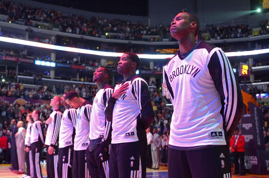 Brooklyn Nets center Jason Collins, right, listens to the national anthem prior to an NBA basketball game against the Los Angeles Lakers, Sunday, Feb. 23, 2014, in Los Angeles. Collins signed a 10-day contract with the Nets earlier Sunday. The 35-year-old center revealed at the end of last season he is gay, but he was a free agent and had remained unsigned. (AP Photo/Mark J. Terrill)