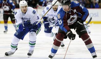 FILE - In this March 24, 2013, file photo, Vancouver Canucks defenseman Chris Tanev, left, defends Colorado Avalanche right wing Milan Hejduk, right, of Czech Republic, in an NHL hockey game in Denver. Hejduk, 38, is retiring from the NHL after 14 seasons, all with the Avalanche. (AP Photo/Chris Schneider, File)