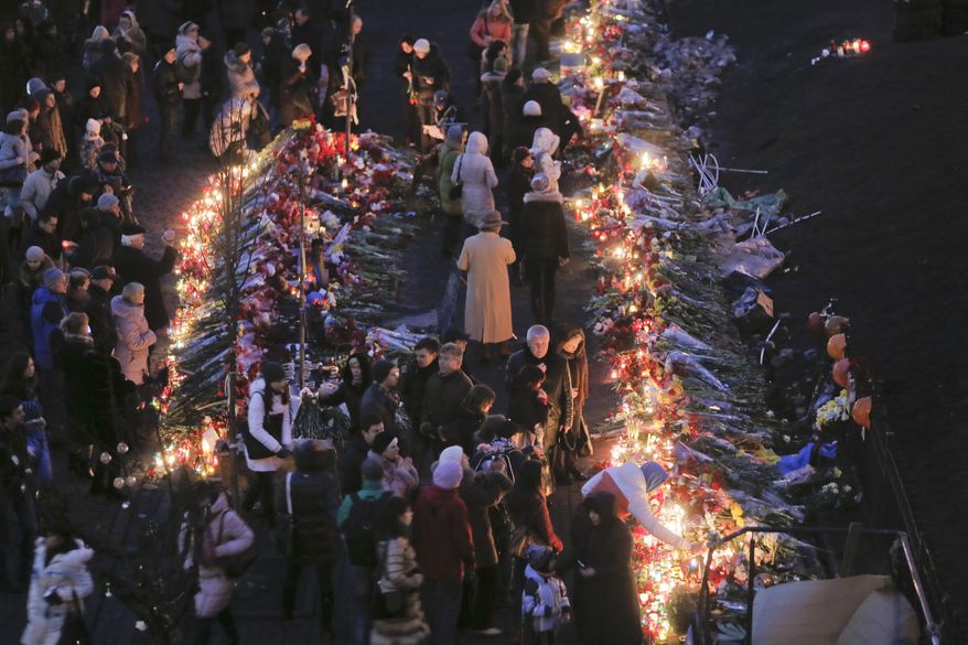People lay flowers and lit candles at one of the barricades heading to Independence Square,Kiev, the epicenter of the country's recent unrest, on a mourning day Monday, Feb. 24, 2014. Ukraine’s acting government issued a warrant Monday for the arrest of President Viktor Yanukovych, last reportedly seen in the pro-Russian Black Sea peninsula of Crimea, accusing him of mass crimes against protesters who stood up for months against his rule. (AP Photo/Efrem Lukatsky)