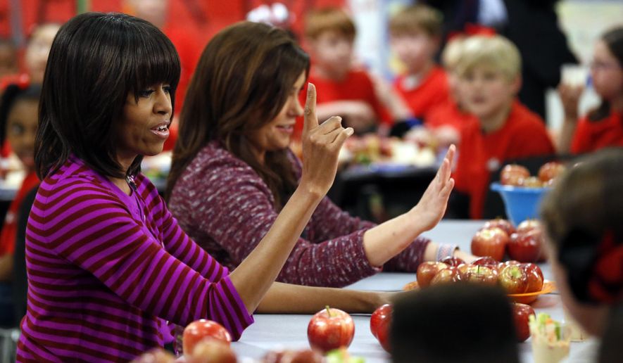 FILE - This Feb. 27, 2013 file photo shows first lady Michelle Obama and Food Network chef Rachel Ray discussing lunches with students from the Eastside and Northside Elementary Schools in Clinton, Miss. Moving beyond the lunch line, new rules expected to be proposed by the White House and the Agriculture Department Tuesday, Feb. 25, 2014, would limit marketing of unhealthy foods in schools, phasing out the advertising of sugary drinks and junk foods around school campuses and ensuring that other promotions in schools are in line with health standards that apply to school foods. (AP Photo/Rogelio V. Solis, File)