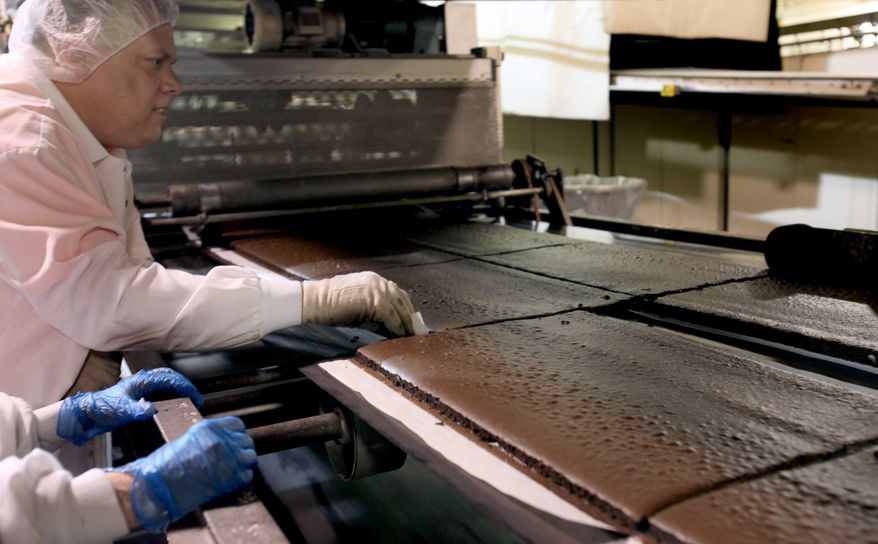 Shawn Agnew, 50, of Westland inspects chocolate cake at Awrey's Bakery in Livonia, Mich., on Feb. 17, 2014. It was a year ago that Awrey's Bakery, one of the few remaining iconic Detroit-area brands, avoided permanent closure in a down-to-the-wire purchase deal. The new buyers, Michigan residents Ron Beebe and James McColgan, bought the Livonia bakery from a pair of out-of-state private equity firms just hours before its equipment was to be sold at liquidation auction. The 200-some Awrey's employees were already out the door. In their place were auctioneers. (AP Photo/Detroit Free Press, Jessica J. Trevino) DETROIT NEWS OUT; NO SALES