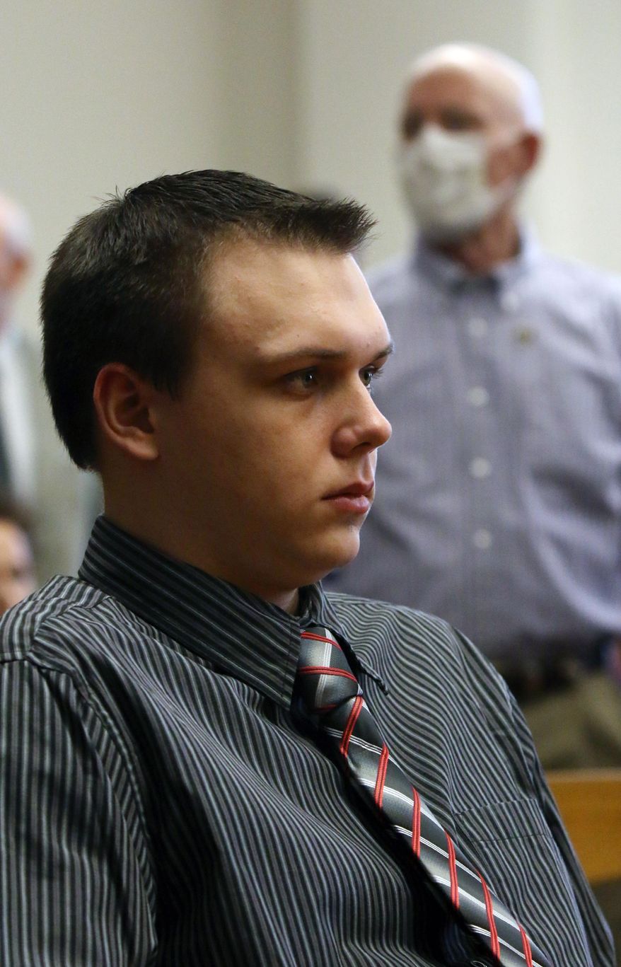 Paul Butterfield, standing background, the father of slain Michigan State Police Trooper Paul Butterfield II stands during a break in the murder trial of Eric Knysz, seated foreground, on Tuesday, Feb. 25, 2014, in Ludington, Mich. Butterfield is wearing a mask to protect himself as he fights leukemia. Knysz is charged in the September 2013 shooting death of the state trooper during a traffic stop in rural Mason County. (AP Photo/The Muskegon Chronicle, Ken Stevens) ALL LOCAL TV OUT; LOCAL TV INTERNET OUT.
