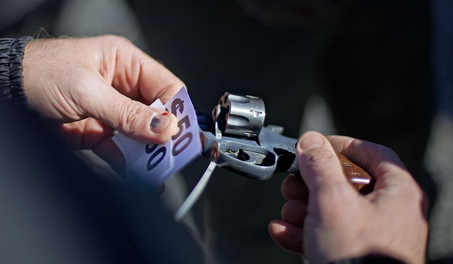 In this file photo, a police officer inspects a revolver turned in to exchange for money during a gun buyback in Atlanta on Jan. 16, 2014. Lawmakers in the North Dakota House of Representatives are considering a bill that would forbid the state's law enforcement agencies from conducting gun-buyback programs. (Associated Press)