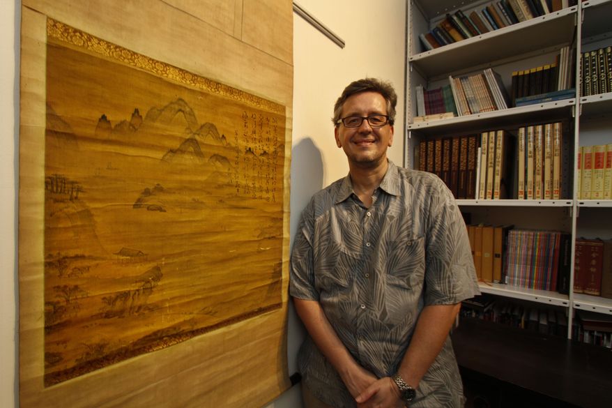In this photo taken on Feb. 20, 2014, Shawn Eichmann, curator of asian art for the Honolulu Museum of Art, poses next to a 16th century Korean painting in Honolulu. The museum discovered two paintings from late 16th-century Korea in its collection. Museum officials expect to receive grant money to send the painting shown to South Korea for conservation, before a grand unveiling for the two when it is returned. (AP Photo/The Star-Advertiser, Dennis Oda)