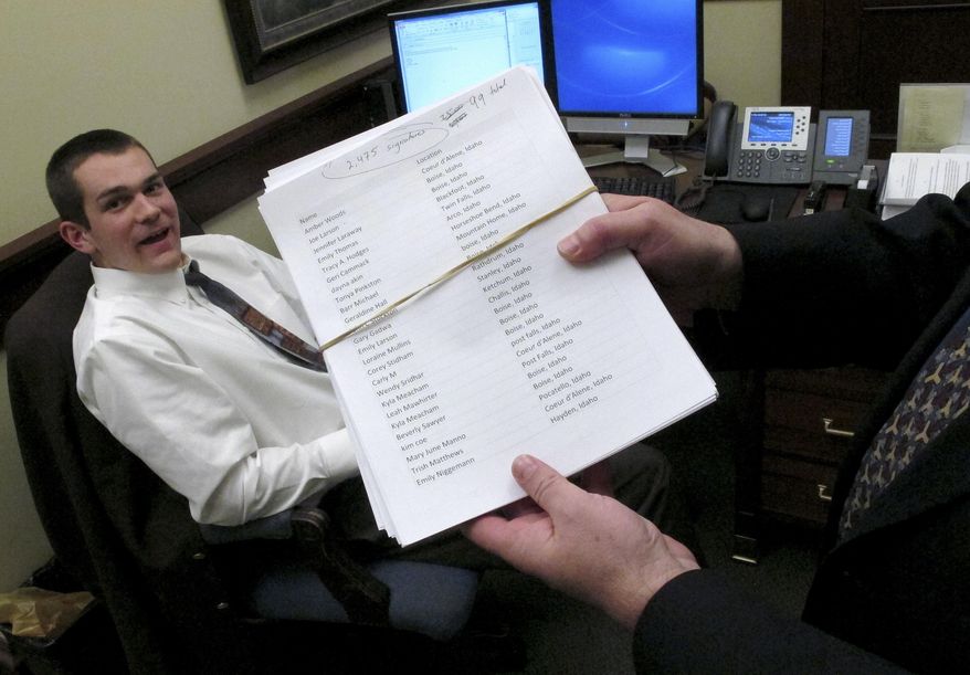 Dain Johnson, an intern in Gov. C.L. "Butch" Otter's office, sorted through more than 110,000 signatures from around the country urging Otter to veto a bill that stiffens penalties for people who secretly film agriculture operations Wednesday, Feb. 26, 2014, in Boise, Idaho. About 2,475 of the signatures were from Idaho residents, Johnson said. The Idaho House voted 56-14 on Wednesday to send the bill to Otter's desk, though the Republican governor hasn't publicly stated his intentions, he's expected to sign the bill. (AP Photo/John Miller)