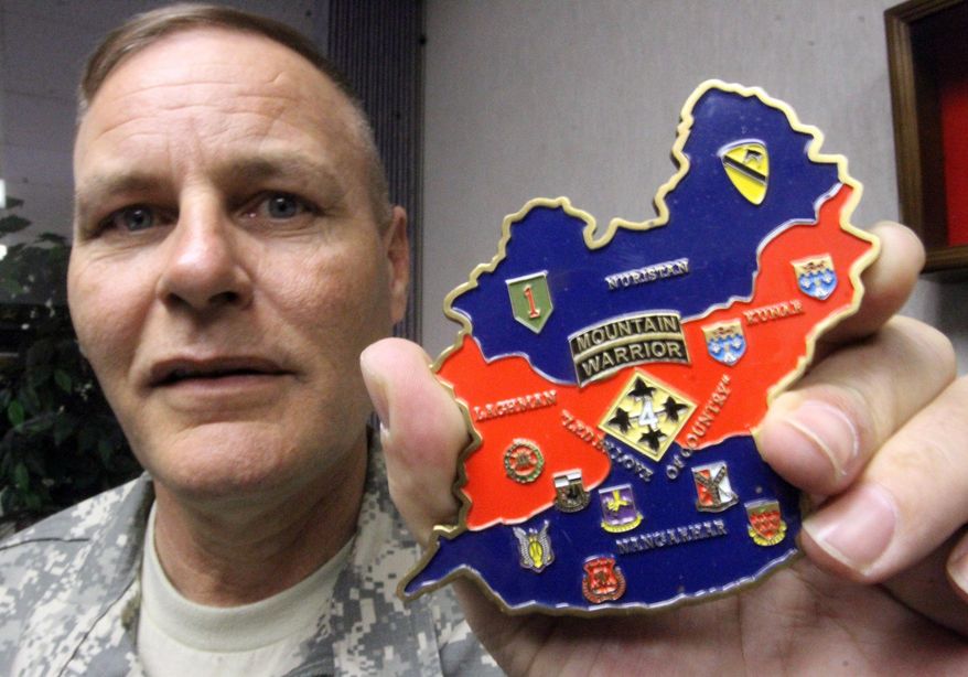 ADVANCE FOR MONDAY MARCH 3 - In this Feb. 19, 2014 photo, Garrison CSM Michael A. Mendoza shows a large "coin" from Afghanistan in El Paso, Texas. Almost any officer or senior noncommissioned officer at Fort Bliss has a collection of coins they proudly show off in their work areas. These coins, called commander's coins or challenge coins, can tell a soldier's life story. They detail where they've been stationed, what units they've served in and where they've deployed. Commanders and senior NCOs hand out these coins as a way to thank a soldier for a job well done and going beyond the call of normal duty.(AP Photo/The El Paso Times, Rudy Gutierrez) EL DIARIO OUT; JUAREZ MEXICO OUT