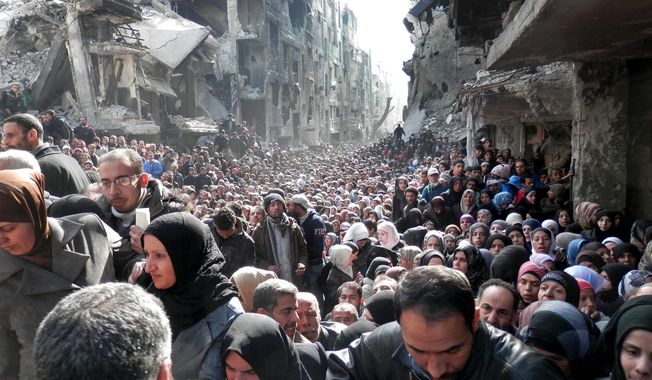 Residents of the besieged Palestinian camp of Yarmouk line up to receive food supplies in Damascus. A United Nations official is calling on warring sides in Syria to allow aid workers to resume distribution of food and medicine in the capital. (United Nations Relief and Works Agency via associated press)