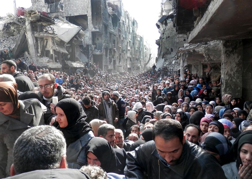 Residents of the besieged Palestinian camp of Yarmouk line up to receive food supplies in Damascus. A United Nations official is calling on warring sides in Syria to allow aid workers to resume distribution of food and medicine in the capital. (United Nations Relief and Works Agency via associated press)