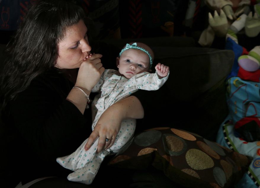 Jennifer Fontaine kisses her baby daughter, Morgan, at her parents' home in Methuen, Mass. on Tuesday, Feb. 25, 2014. After Fontaine's standard prenatal screening suggested her fetus might have Edwards syndrome, a doctor suggested a fetal DNA test, which suggested her fetus was fine. A simple test that looks for fetal DNA in a pregnant woman's blood is far more accurate at detecting or ruling out Down syndrome and other common chromosome disorders than other screening methods used now, a major study finds. (AP Photo/Elise Amendola)