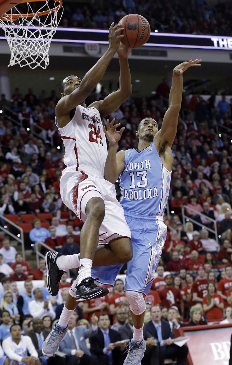 North Carolina's J.P. Tokoto (13) defends as North Carolina State's T.J. Warren (24) drives to the basket during the first half of an NCAA college basketball game in Raleigh, N.C., Wednesday, Feb. 26, 2014. (AP Photo/Gerry Broome)