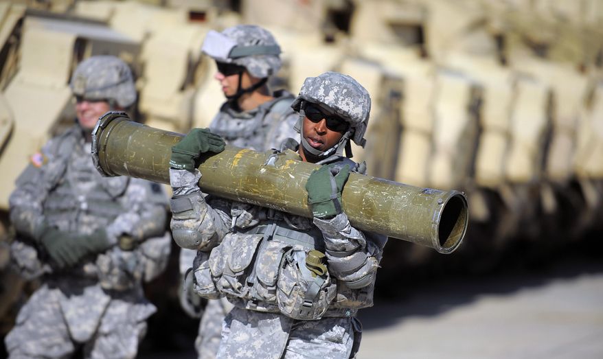 U.S. Army Corp. Jacqueline Beachum carries a 65-pound T.O.W. missile several yards before loading the dummy missile to the launcher of a Bradley Fighting Vehicle during a physical demands study, Tuesday, Feb. 25, 2014, in Ft. Stewart, Ga. The Army is conducting a study that will determine how all soldiers, including women, for the first time, will be deemed fit to join its fighting units from infantry platoons to tank crews. (AP Photo/Stephen B. Morton)