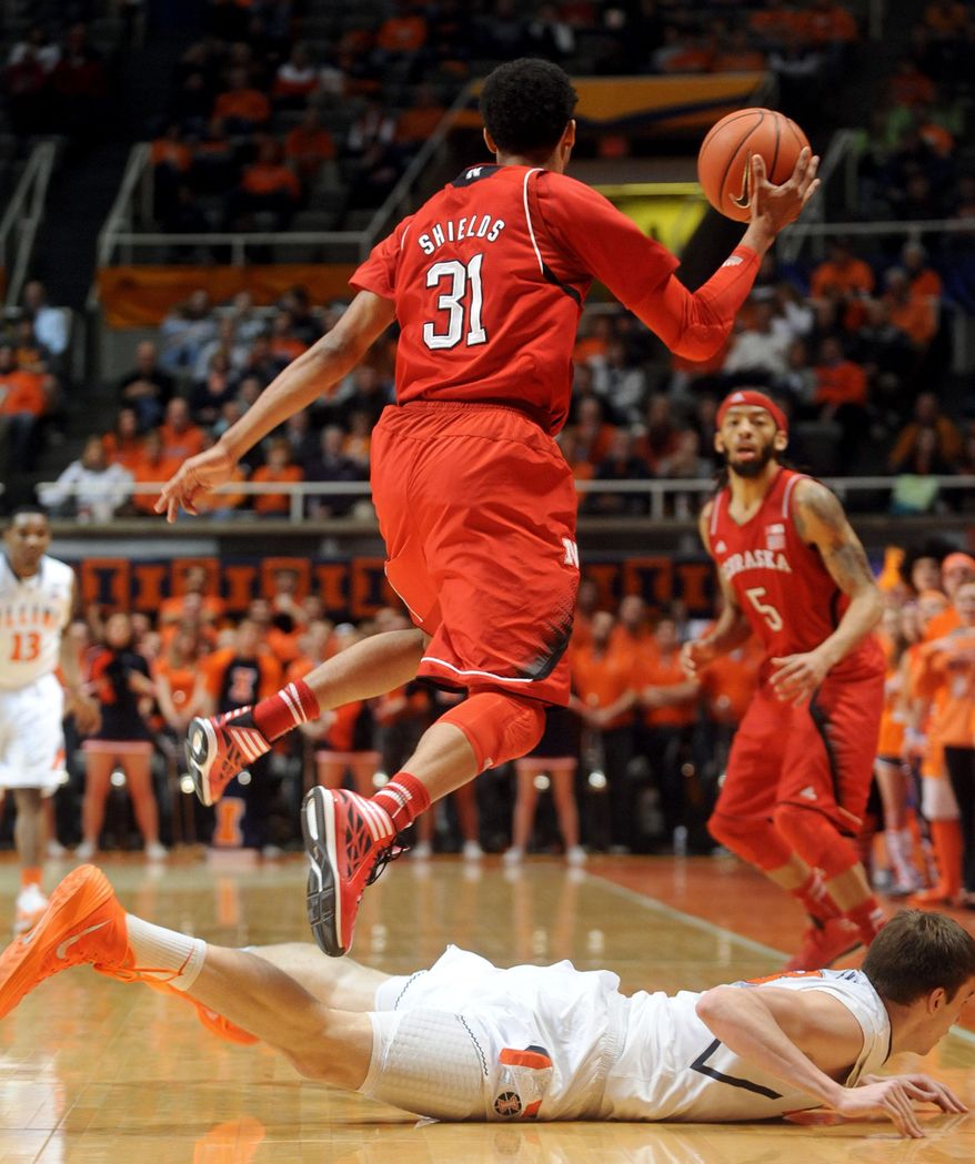 While jumping over Illinois' Jon Ekey (33), Nebraska's Shavon Shields (31) takes over the ball and prepares to make a pass to Terran Petteway (5) during the first half of an NCAA college basketball game Wednesday, Feb. 26, 2014, in Champaign, Ill. (AP Photo/Heather Coit)