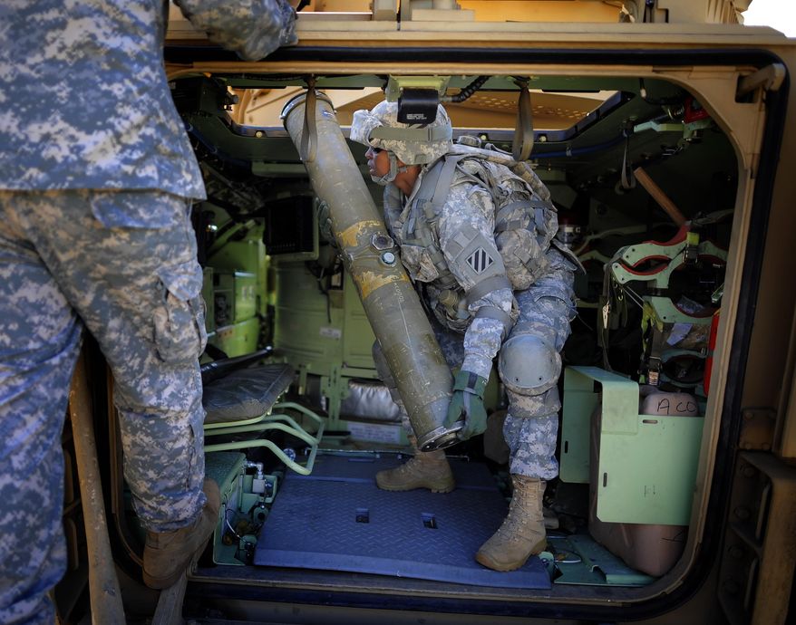U.S. Army Corp. Jacqueline Beachum lifts a 65-pound dummy T.O.W. missile into the launcher of a Bradley Fighting Vehicle during a physical demands study, Tuesday, Feb. 25, 2014, in Ft. Stewart, Ga. The Army is conducting a study that will determine how all soldiers, including women, for the first time, will be deemed fit to join its fighting units from infantry platoons to tank crews. (AP Photo/Stephen B. Morton)