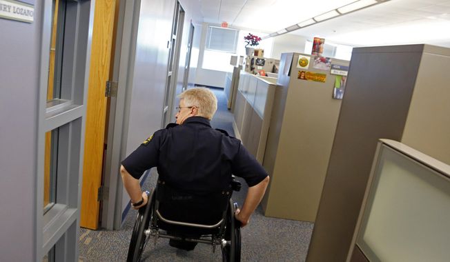 Dallas police Lt. Tony Crawford pushes himself to his office at the Dallas Police Department Jack Evans Police Headquarters building Tuesday, Feb. 25, 2014 in Dallas. Crawford was shot in the line of duty more than two decades ago while working patrol in Lakewood. The bullet severed his spinal column, paralyzing him from the waist down. Crawford returned to desk duty the following year after extensive rehabilitation.  (AP Photo/The Dallas Morning News, G.J. McCarthy)  MANDATORY CREDIT; MAGS OUT; TV OUT; INTERNET USE BY AP MEMBERS ONLY; NO SALES