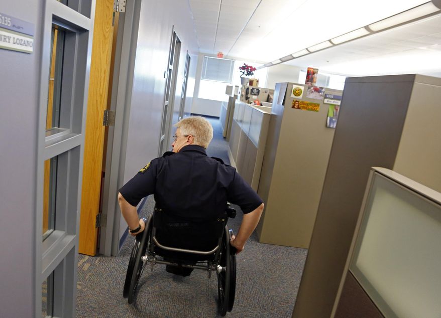 Dallas police Lt. Tony Crawford pushes himself to his office at the Dallas Police Department Jack Evans Police Headquarters building Tuesday, Feb. 25, 2014 in Dallas. Crawford was shot in the line of duty more than two decades ago while working patrol in Lakewood. The bullet severed his spinal column, paralyzing him from the waist down. Crawford returned to desk duty the following year after extensive rehabilitation. (AP Photo/The Dallas Morning News, G.J. McCarthy) MANDATORY CREDIT; MAGS OUT; TV OUT; INTERNET USE BY AP MEMBERS ONLY; NO SALES