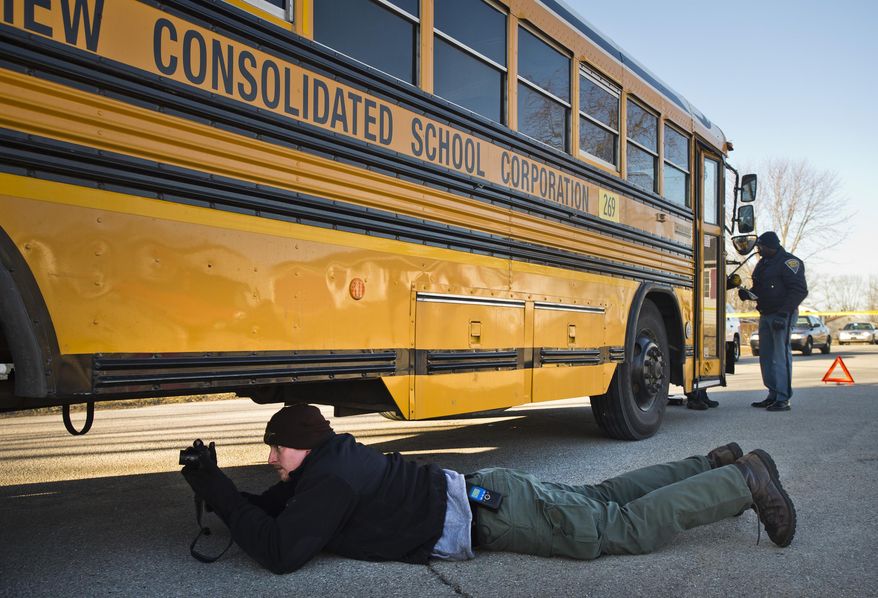 Detective Kevin Abner of the Bartholomew County Sheriff's Department investigates an accident in Taylorsville, Ind. after two children were struck by a school bus Thursday, Feb. 27, 2014. Bartholomew County sheriff's Chief Deputy Todd Noblitt says a 9-year-old girl had serious injuries and was flown to Riley Hospital for Children in Indianapolis. Noblitt tells The Republic that a 6-year-old boy was taken to Columbus Regional Hospital. (AP Photo/The Republic, Andrew Laker)