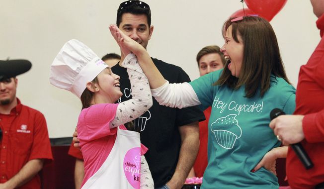 Chloe Stirling, 11, trades a high-five with her mom, Heather, at Triad Middle School near Troy, Ill., Thursday, Feb. 27, 2014, after learning a local plumbing company will build her a commercial kitchen for her cupcake business. Madison County health officials shut down the girl's $200-a-month operation last month after concluding her kitchen wasn't a commercial one requiring such things as a permit and inspection. The announcement came while the Stirlings and Chloe's peers watched the family's taped appearance on the "Rachael Ray" show. (AP Photo/Belleville News-Democrat, Derik Holtmann)