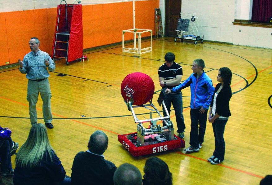 ADVANCE FOR MONDAY, MARCH 3 - In this photo taken on Feb. 18, 2014, science teacher Stewart Kieliszewski, left, talks about the school’s robot during an assembly at Ubley High School in Ubley, Mich. A six-week project to build, program and operate a robot to compete in state robotic games was unveiled at the school to a group of school board members, parents and business representatives. (AP Photo/Huron Daily Tribune, David Shane)