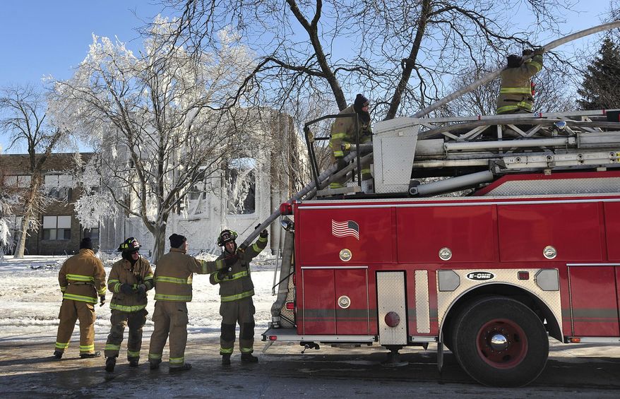 Racine Fire Department firefighters pack up their hose Thursday morning, Feb. 27, 2014 after an early morning fire severely damaged Mitchell Elementary School in Racine, causing the gymnasium roof to collapse. School administrators have canceled classes at the damaged school. (AP Photo/The Journal Times, Scott Anderson)
