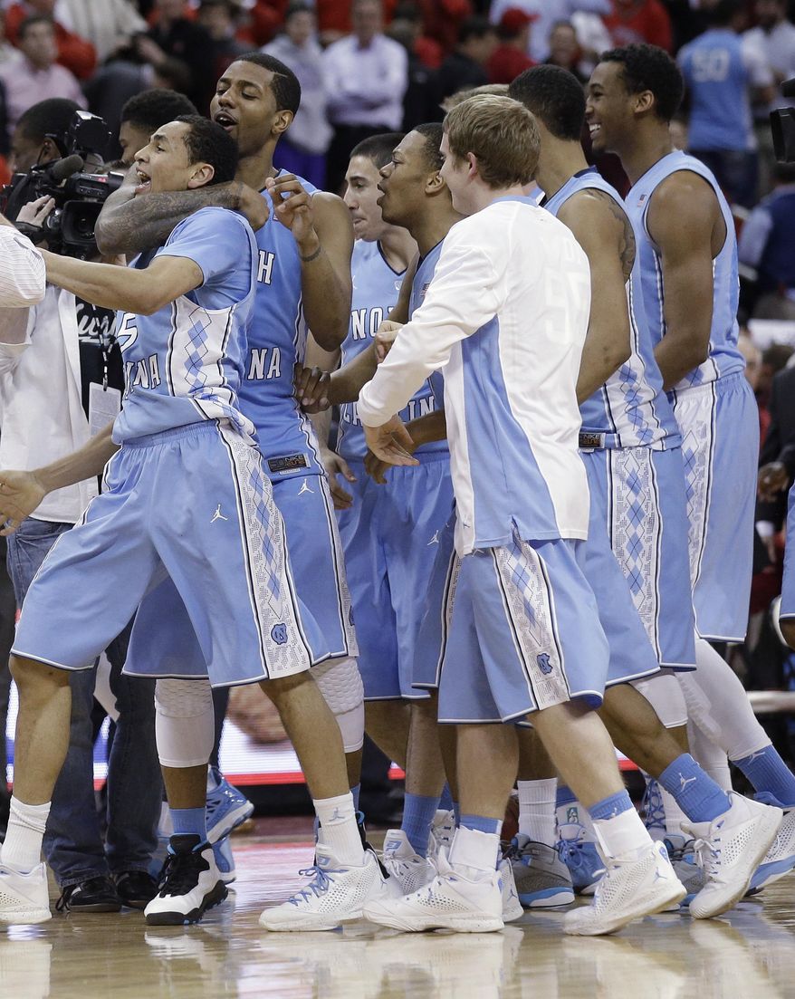 North Carolina's Leslie McDonald hugs Marcus Paige (5) as teammates celebrate Paige's shot in overtime following an NCAA college basketball game in Raleigh, N.C., Wednesday, Feb. 26, 2014. North Carolina defeated North Carolina State 85-84 in overtime. (AP Photo/Gerry Broome)