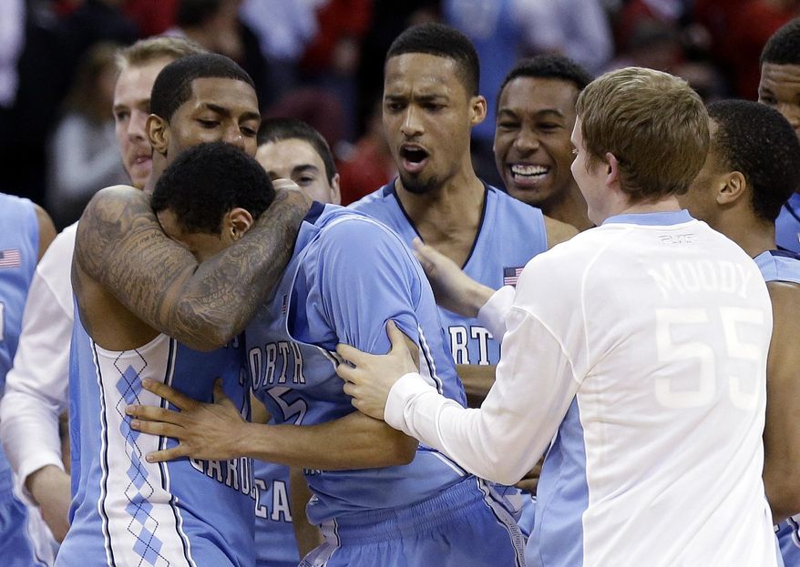 North Carolina's Leslie McDonald, left, hugs Marcus Paige as teammates celebrate Paige's shot in overtime following an NCAA college basketball game in Raleigh, N.C., Wednesday, Feb. 26, 2014. North Carolina defeated North Carolina State 85-84 in overtime. (AP Photo/Gerry Broome)