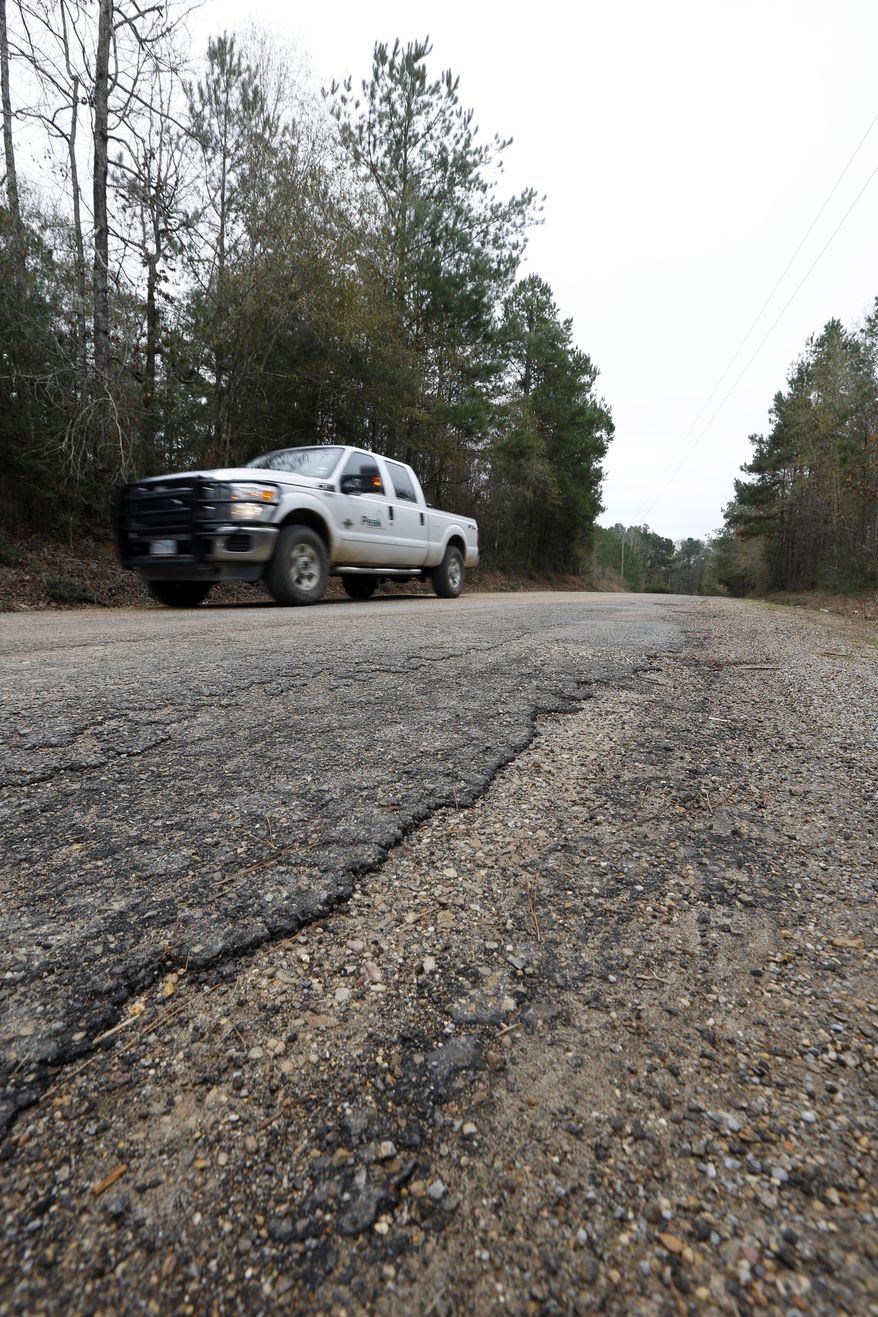In this Dec. 23, 2013 photograph, a pickup truck passes on River Road in Amite County, Miss. County Supervisor Max Lawson says the drilling-based road damage is of great concern throughout the small county as county government has limited funds for road repair. Lawson hopes the oil companies plan a big increase in drilling activity in 2014 in southwest Mississippi does not drain the road repair fund that must cover the entire county. (AP Photo/Rogelio V. Solis)