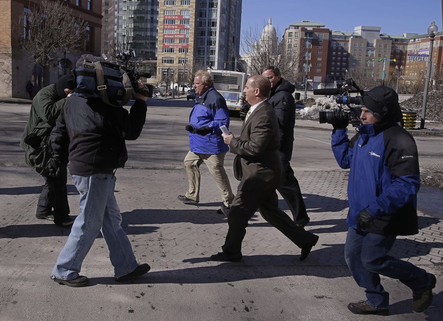 Former Central Falls, RI., mayor Charles Moreau is followed by members of the media as he leaves the Federal Courthouse and walks to his car in Providence, RI., Friday, Feb. 28, 2014. Moreau was released from federal prison Friday after serving just under one year of a two-year sentence. Moreau was released after first pleading guilty to a new charge of accepting a bribe and being sentenced on that charge to time served. As part of the deal, U.S. District Court Judge John McConnell then vacated Moreau's 2012 conviction, allowing him to walk free. (AP Photo/Stephan Savoia)