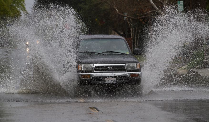 A SUV drives through a flooded portion of a street in Encino, section of Los Angeles Friday, Feb. 28, 2014. The first wave of a powerful Pacific storm spread rain and snow early Friday through much of California, where communities endangered by a wildfire just weeks ago now faced the threat of mud and debris flows. (AP Photo/Ringo H.W. Chiu)