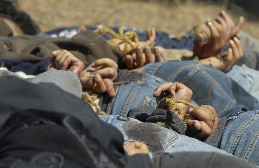 ADVANCE FOR USE SUNDAY, MARCH 2 - FILE - In this Dec. 4, 2008, file photo, bodies from a total of 13 bullet-ridden men, with their hands tied behind their backs, victims of the drug war involving Joaquin “El Chapo” Guzman's Sinaloa cartel, lie in a field near the town of San Ignacio in the pacific state of Sinaloa, Mexico. Guzman and his cohorts waged an increasingly bloody war over the year with rival gangs. (AP Photo/File)