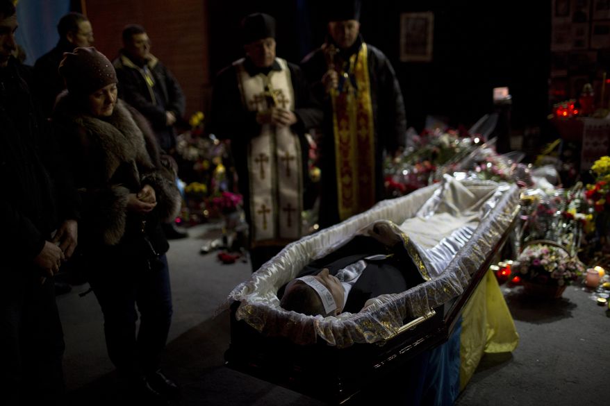 The body of anti-Yanukovych protester Bailuk Alexander, 40, killed in a recent clash with riot police in Kiev's Independence Square, is seen in a coffin during his funeral on Friday, Feb. 28, 2014, in Ukraine. Official reports say 82 people were killed in severe clashes between opposition activists and riot police. (AP Photo/Emilio Morenatti)