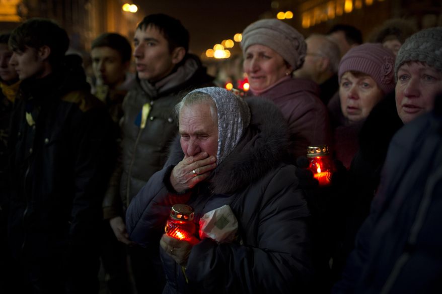 People react during the funeral of anti-Yanukovych protester Bailuk Alexander, 40, killed in a recent clash with riot police in Kiev's Independence Square, Ukraine, Friday, Feb. 28, 2014. Official reports say 82 people were killed in severe clashes between opposition activists and riot police. (AP Photo/Emilio Morenatti)