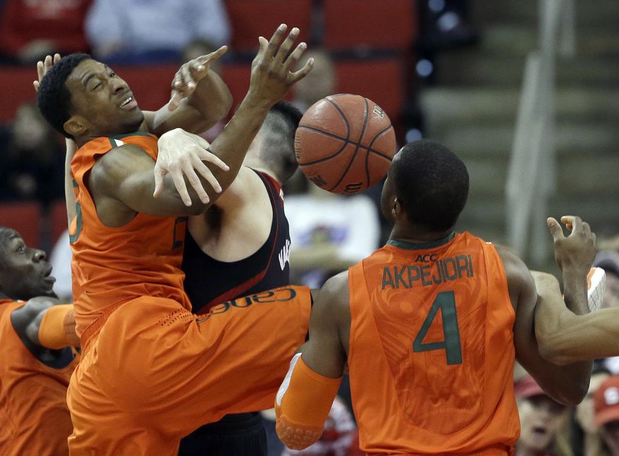 Miami's Garrius Adams, left, and Raphael Akpejiori (4) struggle with North Carolina State's Jordan Vandenberg for a rebound during the first half of an NCAA college basketball game in Raleigh, N.C., Saturday, March 1, 2014. (AP Photo/Gerry Broome)
