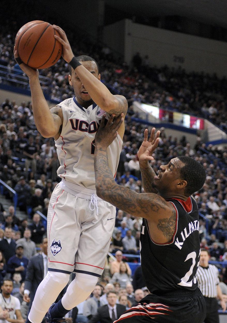 Connecticut's Shabazz Napier (13) and Cincinnati's Sean Kilpatrick (23) fight for a rebound during the first half of an NCAA college basketball game in Hartford, Conn., Sunday, March 1, 2014. (AP Photo/Fred Beckham)