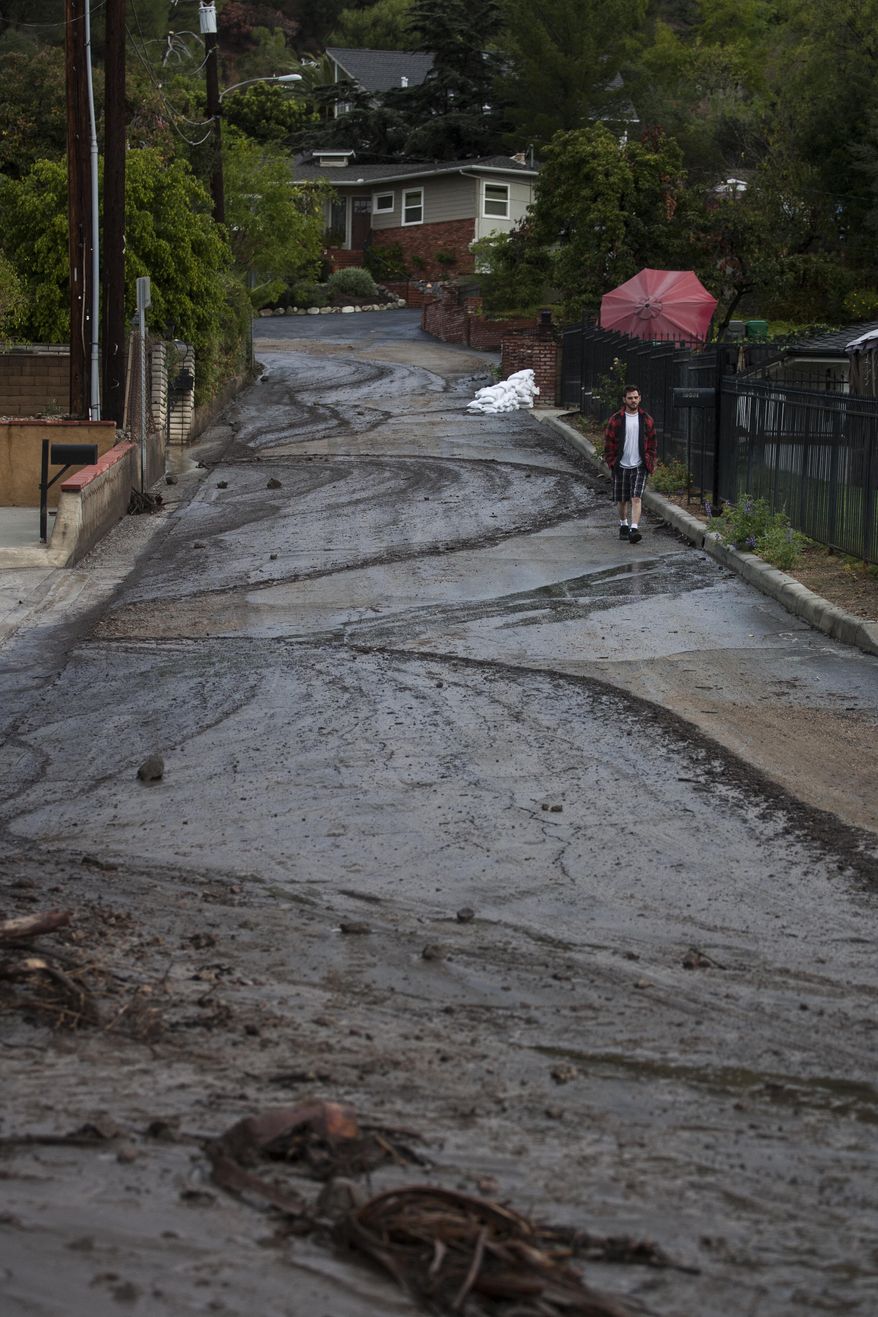 A man walks along the mud and debris on the Highcrest Road in Glendora, Calif. on Saturday, March 1, 2014. A burst of heavy showers before dawn Saturday impacted wildfire-scarred mountainsides above foothill suburbs east of Los Angeles, causing another round of mud and debris flows in the city of Glendora. (AP Photo/Ringo H.W. Chiu)