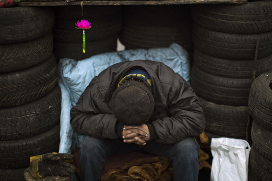An anti-Yanukovych protester sleeps as he guards a barricade in Kiev's Independence Square, Saturday, March 1, 2014. The pro-Russian prime minister of Ukraine's restive Crimea is claiming control of all military forces, police and other security services in the region. In a statement reported by local and Russian news agencies on Saturday, Sergei Aksenov declares that the armed forces, the police, the national security service and border guards will answer only to his orders. He says that any commanders who don't agree should leave their posts. (AP Photo/Emilio Morenatti)