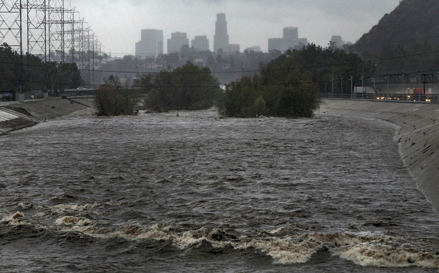 With the Los Angeles skyline in the background, the Los Angeles River flows Friday, Feb. 28, 2014. Two men and their dogs were rescued earlier from the swift waters of the Los Angeles River. A few miles downriver, another man was pulled out and carried to safety. Even with rainfall totals exceeding six inches in some places Friday, the powerful Pacific storm did not put a major dent in a drought that is among the worst in recent California history. (AP Photo/Damian Dovarganes)