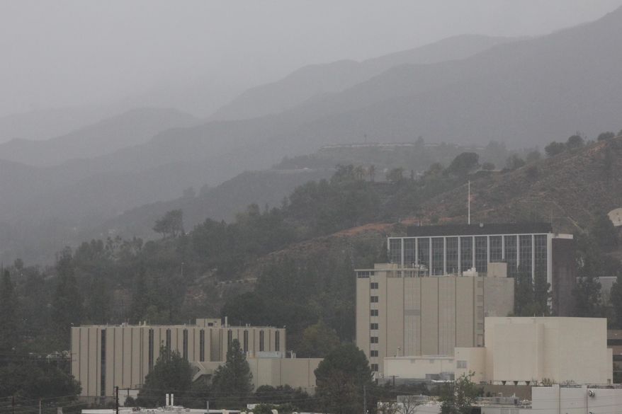 Storm clouds blanket ridges of the San Gabriel Mountains above Los Angeles' northeastern foothill suburbs on Saturday, March 1, 2014. Residents of some 1,200 homes in three foothill cities to the east were under evacuation orders due to danger of debris flows from steep slopes burned bare by recent wildfires. NASA's Jet Propulsion Laboratory is in foreground. (AP Photo/ John Antczak)