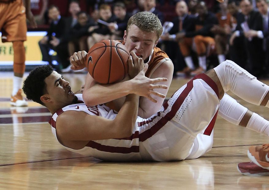 Oklahoma guard Frank Booker, bottom, and Texas forward Connor Lammert scramble for a loose ball during the first half of an NCAA college basketball game in Norman, Okla., Saturday, March 1, 2014. (AP Photo/Alonzo Adams)