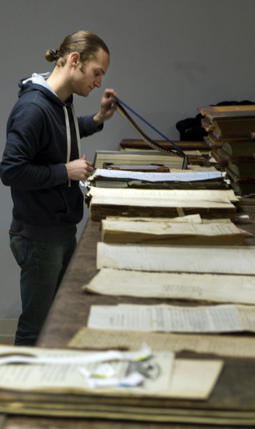 In this Feb. 26, 2014 photo, Monroe County archivist Jon Weiler works on repairing and protecting aging county records in Bloomington, Ind. County recorder Jim Fielder and Weiler are working to establish a library of the county's old permanent records that include meeting minutes, property records, old school records and marriage licenses. (AP Photo/The Herald-Times, David Snodgress)
