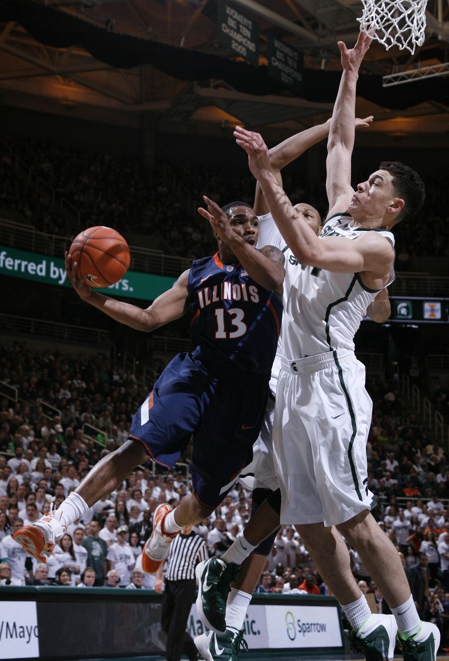 Illinois' Tracy Abrams (13) dishes off against Michigan State's Gavin Schilling, right, and Adreian Payne during the first half of an NCAA college basketball game, Saturday, March 1, 2014, in East Lansing, Mich. (AP Photo/Al Goldis)