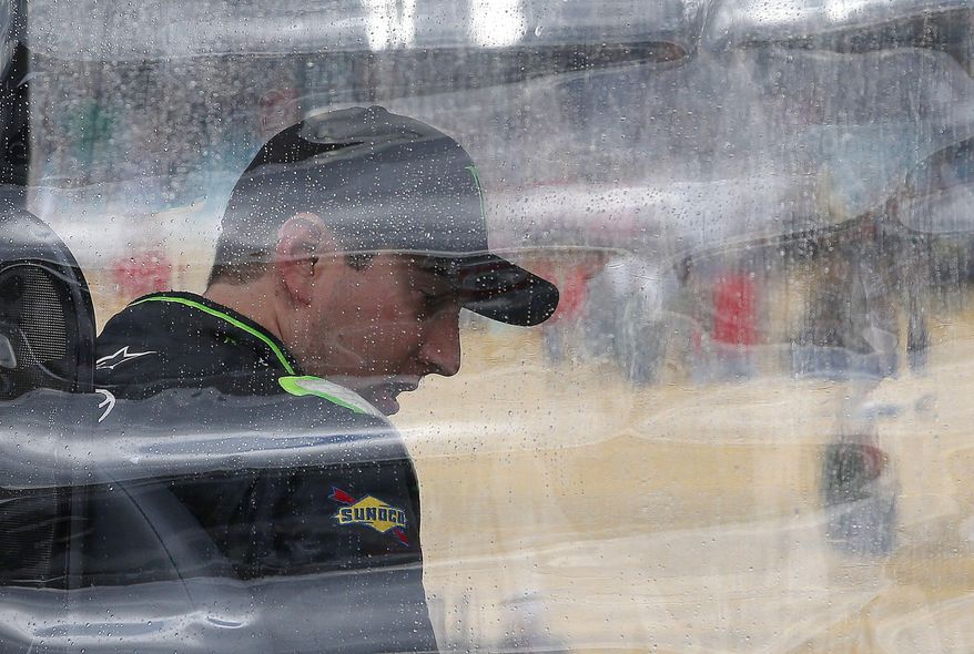 Kyle Busch waits out a rain delay at his team stall on pit road during a NASCAR Nationwide auto race Saturday, March 1, 2014, in Avondale, Ariz. (AP Photo/Ross D. Franklin)