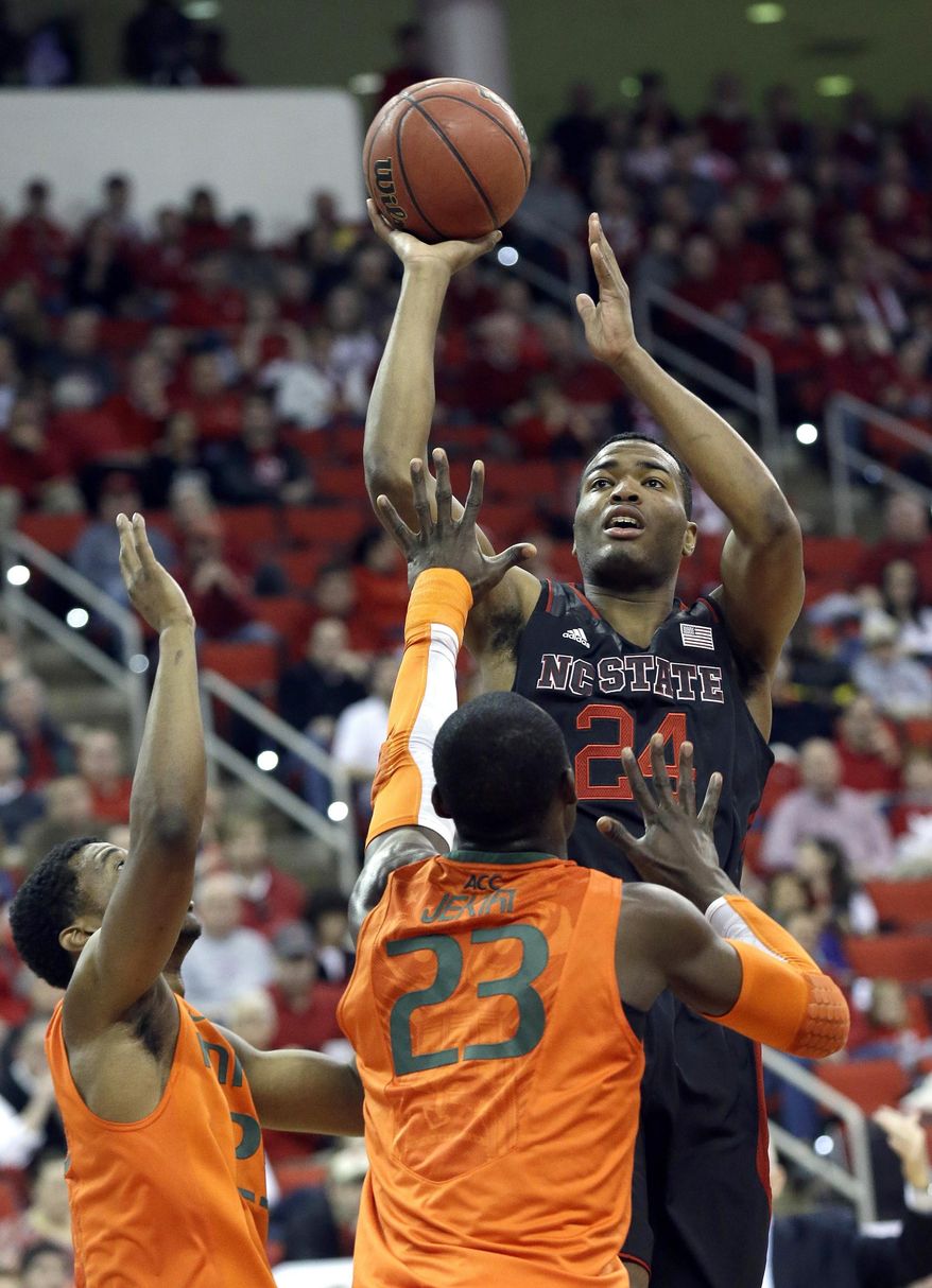 North Carolina State's T.J. Warren (24) shoots while Miami's Tonye Jekiri (23) and Garrius Adams, left, defend during the first half of an NCAA college basketball game in Raleigh, N.C., Saturday, March 1, 2014. (AP Photo/Gerry Broome)