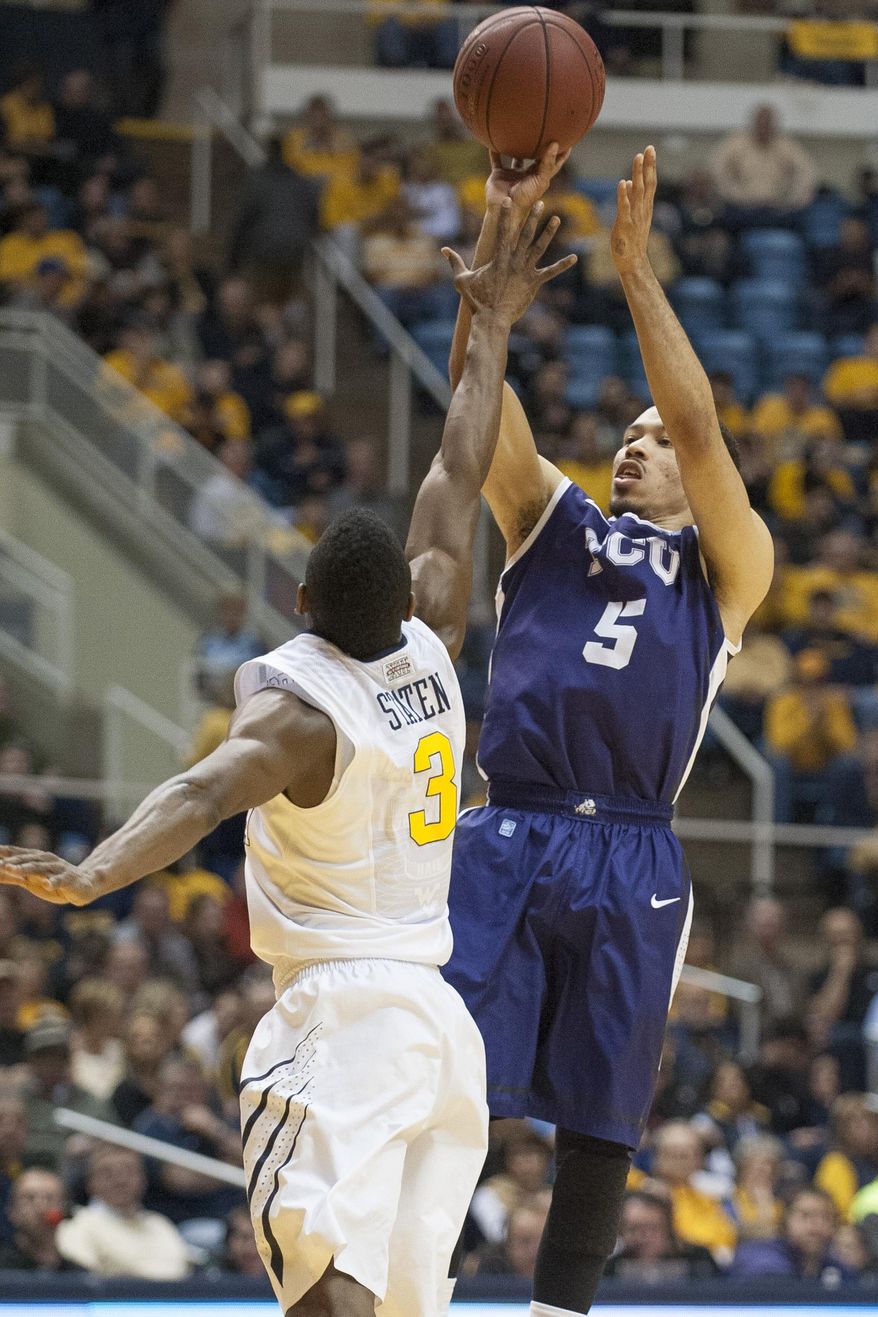 TCU's Kyan Anderson, right, looks to shoot over West Virginia's Juwan Staten during the first half of an NCAA college basketball game Saturday, March 1, 2014, in Morgantown, W.Va. (AP Photo/Andrew Ferguson)