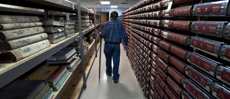 In this Feb. 26, 2014 photo, Jim Fielder, Monroe County recorder, walks down an aisle of bound volumes of records in the new county archive in Bloomington, Ind. Fielder and county archivist Jon Weiler are working to establish a library of the county's old permanent records that include meeting minutes, property records, old school records and marriage licenses. (AP Photo/The Herald-Times, David Snodgress)