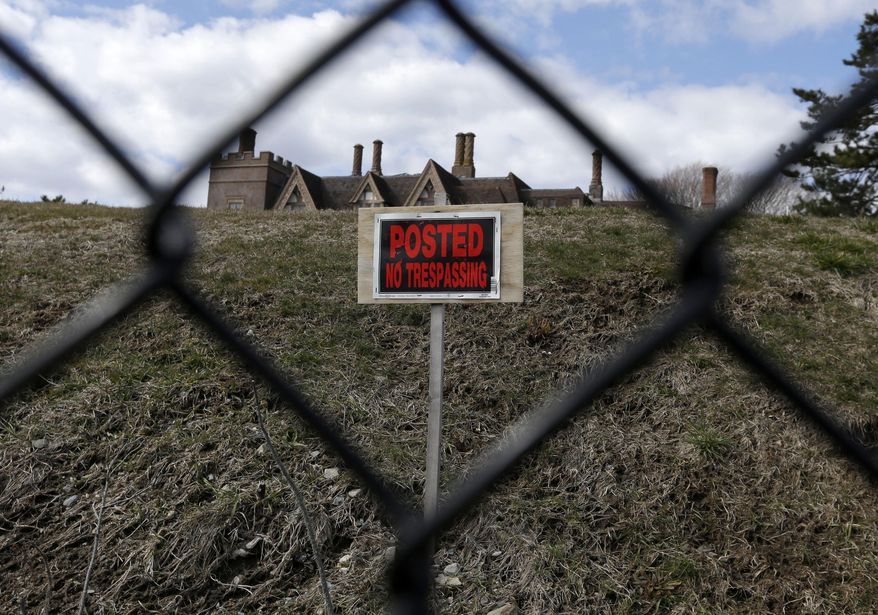 FILE - In this Wednesday, March 27, 2013 file photo a "no trespassing" sign and the roof of a mansion are visible from the path of the Cliff Walk, in Newport, R.I. Sixteen months after Superstorm Sandy washed away parts of Newport's famous Cliff Walk, a large swath remains closed. But officials say they expect the entire 3.5-mile trail will open again June 13 after millions of dollars is spent on repairs to the centuries-old walk, which attracts hundreds of thousands of visitors a year and is Rhode Island's most visited tourist attraction. (AP Photo/Steven Senne, File)