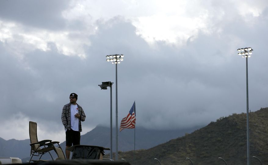 A spectator looks around as storm clouds move in for a rain-shortened NASCAR Nationwide auto race on Saturday, March 1, 2014, in Avondale, Ariz. Kyle Busch was declared the winner. (AP Photo/Ross D. Franklin)